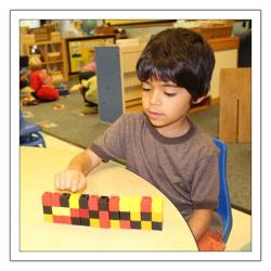 Boy sitting at table playing with small, multicolored blocks
